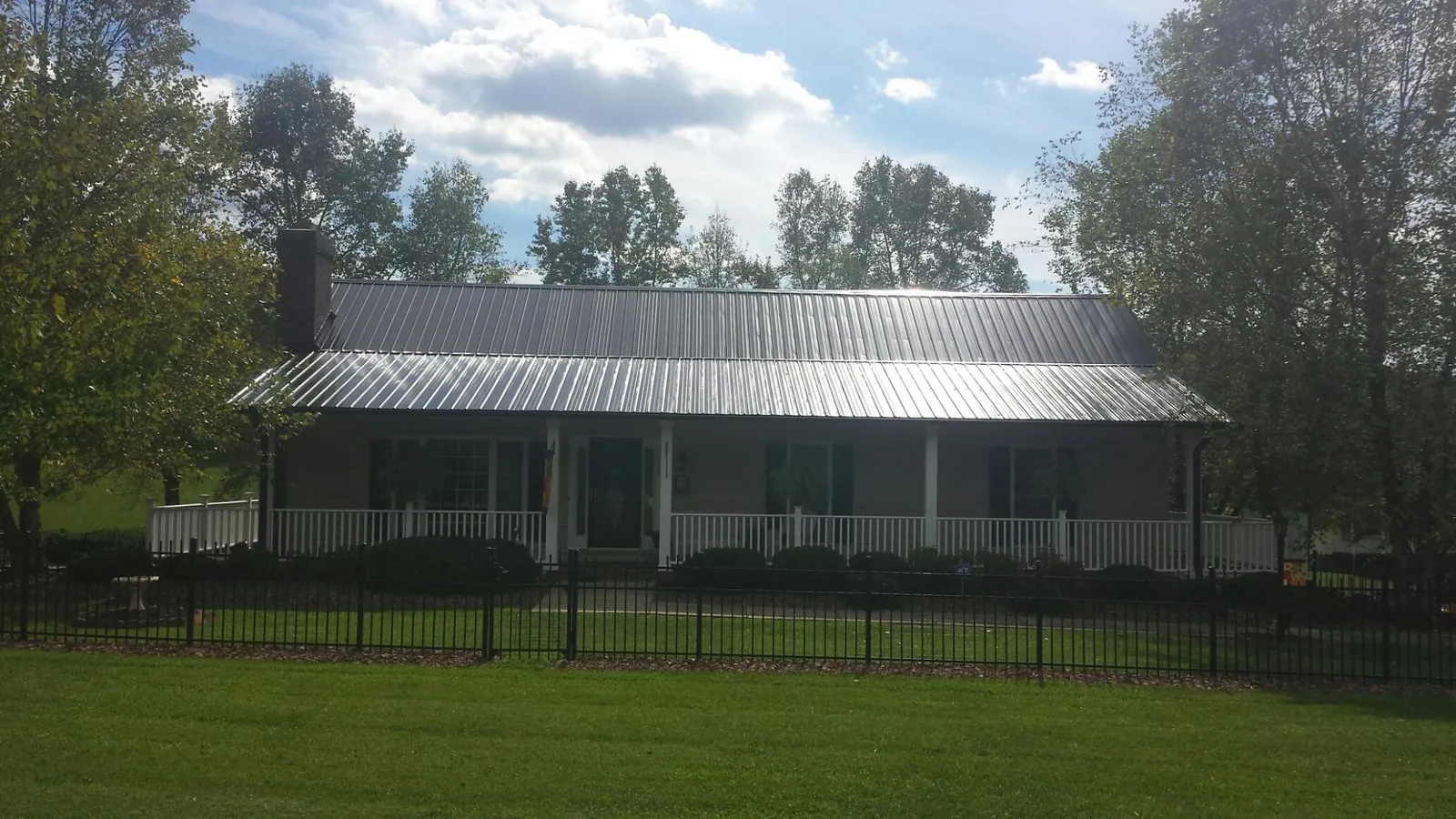 Gray metal roof on a brick ranch with a full width front porch — Gutter Guard Installation work by our crew in Charlotte